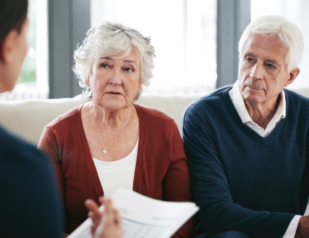 An older couple reviewing disability-claim paperwork with an advisor